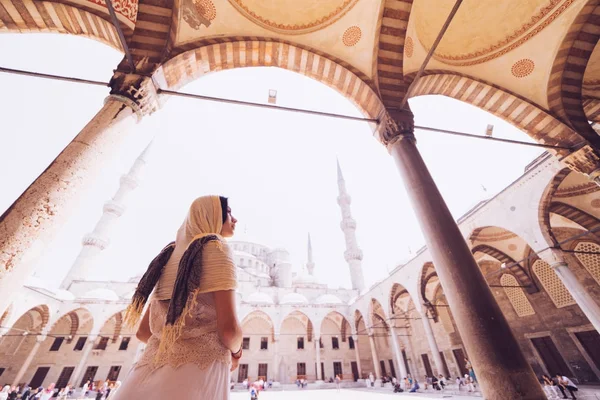 Kafasına eşarp genç kadın Gezgin ile geri Sultanahmet Camii arka plan üzerinde duruyor. Yaz tatillerinde seyahat