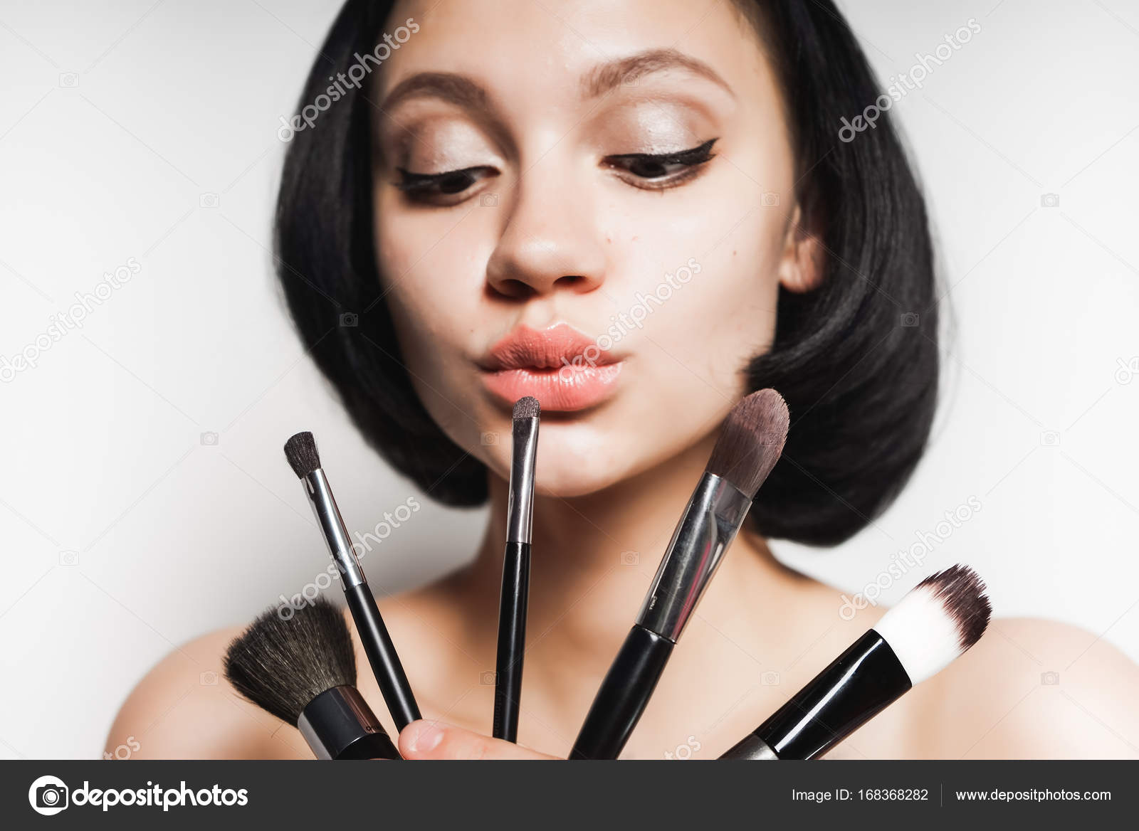 Nice Girl With Short Black Hair Pensively Chooses Makeup Brushes