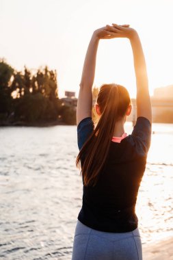 Sahilde günbatımı spor kıyafetli kız