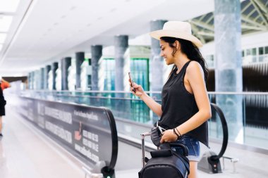 Havaalanında Smartphone kullanan kadın seyahat. Cep telefonu uygulaması terminal ya da tren istasyonu ile yatılı zaman kontrol genç Doğu yolcusu. Turizm tatil.