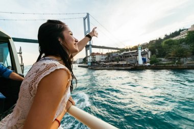 Elleri kadar yükselterek ve modern bir köprü, günbatımı, gezi için işaret eden genç mutlu kız özgürlük