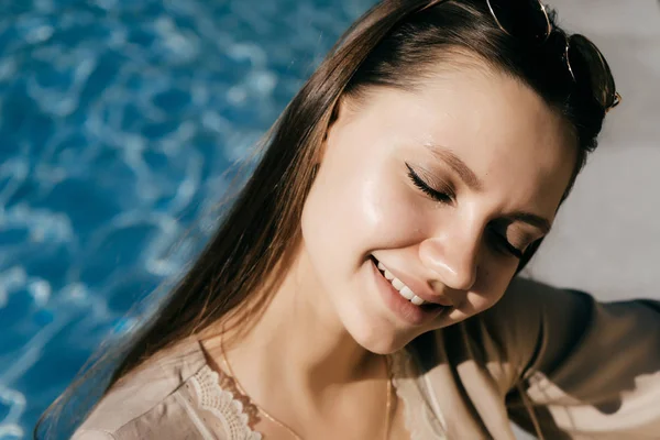 Menina agradável e agradável com cabelos longos sentados à beira da piscina — Fotografia de Stock
