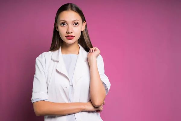 Uma menina em um vestido branco olha assustado para a câmera em um fundo rosa, isolado — Fotografia de Stock