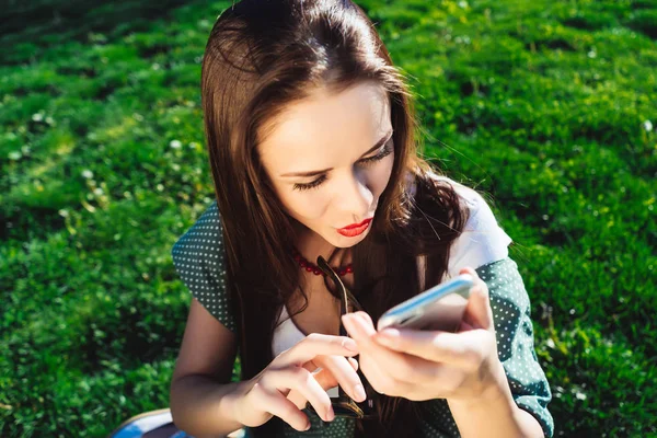 La chica está mirando en el teléfono, mujer de mensajes de texto, sorprendido, hierba fondo de verano — Foto de Stock