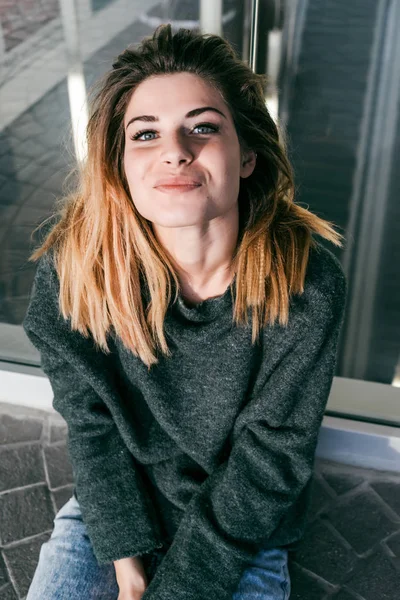 Linda chica en un suéter gris cálido sonriendo y mirando a la cámara — Foto de Stock