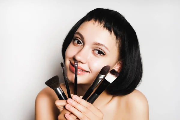 Κοπέλα με κοντά μαλλιά κατέχει ένα πινέλο για το make up και φαίνεται στην κάμερα — Φωτογραφία Αρχείου