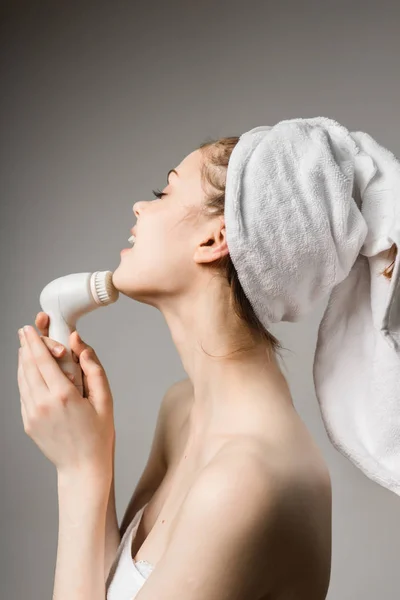 Девушка после душа с полотенцем на голове массирует кожу лица — стоковое фото