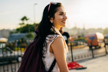 Gün batımında şehirde yürüyüş bir sırt çantası ile kız Gezgin