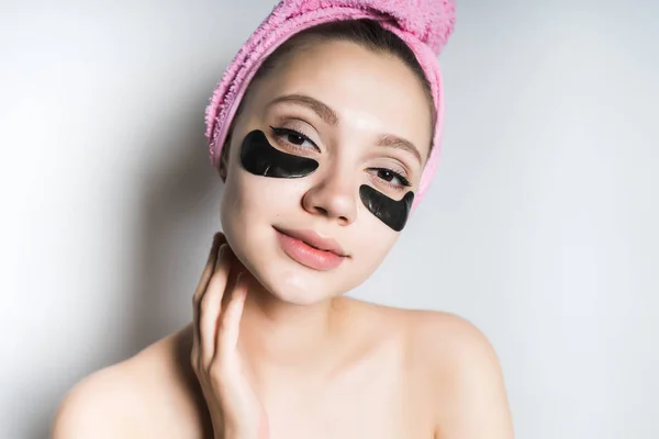 Een vrouw geniet van huid en haar verzorging, een zwart masker onder de ogen — Stockfoto