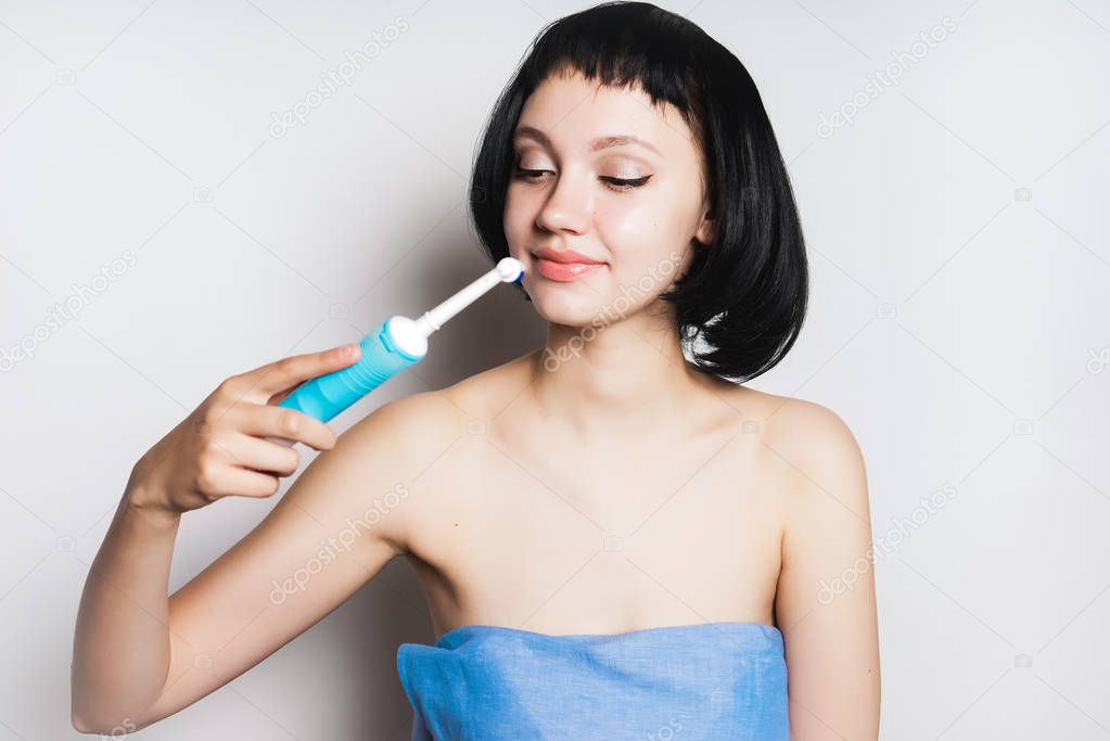 A teenager brushes his teeth with an electric brush, oral hygiene