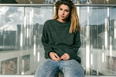 düşünceli bir kız yemyeşil bir saç modeli ve karanlık bir kazak bir şehir sokak oturur