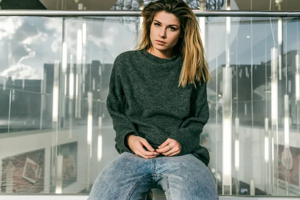 düşünceli bir kız yemyeşil bir saç modeli ve karanlık bir kazak bir şehir sokak oturur