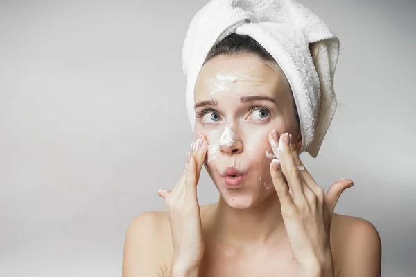 Primer plano de la hermosa joven aplicación de crema con toalla de baño en la cabeza que cubre sus pechos, disfrutando —  Fotos de Stock