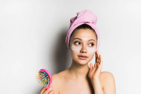 Una hermosa chica después de una ducha sostiene un peine en sus manos y mira coqueta a un lado — Foto de Stock