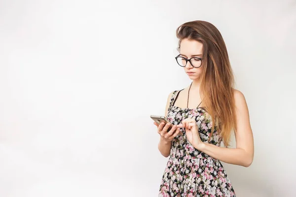 Pretty woman in glasses with long hair and in a dress in a flower use cellphone — Stock Photo, Image