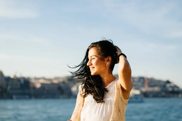 Una studentessa chiude gli occhi ed è felice del tramonto sullo sfondo della città e dell'acqua — Foto Stock