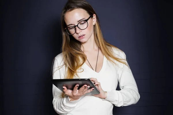 Schönes Mädchen mit großer Brille blickt auf das Tablet, isoliert auf blauem Hintergrund — Stockfoto