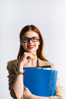 Gözlüklü güzel kızıl saçlı kız kameraya bakar ve bir klasör izole beyaz bir arka plan üzerinde elinde tutan