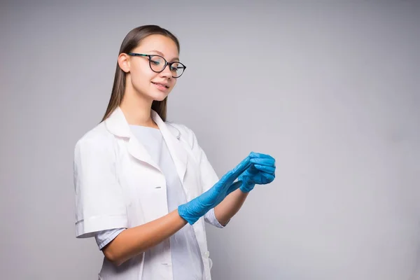 Vackra leende flicka i medicinsk klänning sätter på handskar — Stockfoto