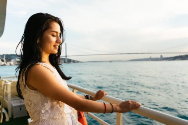 Genç kız gezgin bir yatta seyir ederken rahatlatır, gün batımı ve okyanus bakarak, arka plan üzerinde köprü