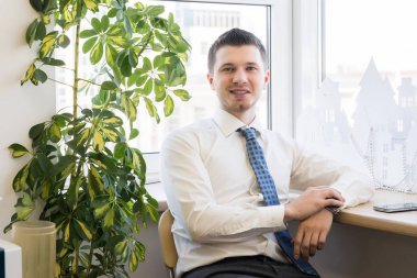 adam bina modeli yanındaki pencere pervazına yakın bir sandalyede oturuyor