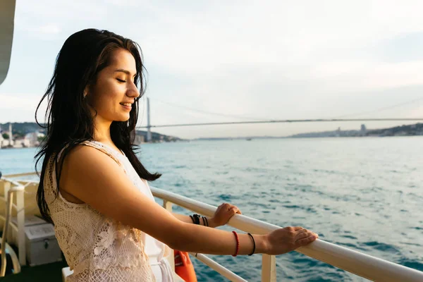 Ung flicka traveler slappnar cruisar på en yacht, titta på solnedgången och ocean, bron på bakgrund — Stockfoto
