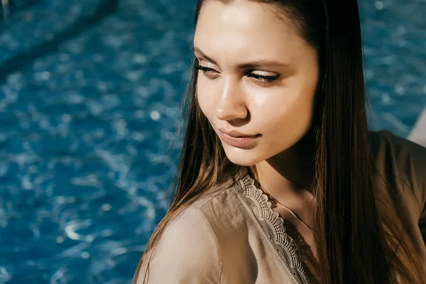 Ung flicka på en bakgrund av en fontän ser ut åt sidan — Stockfoto