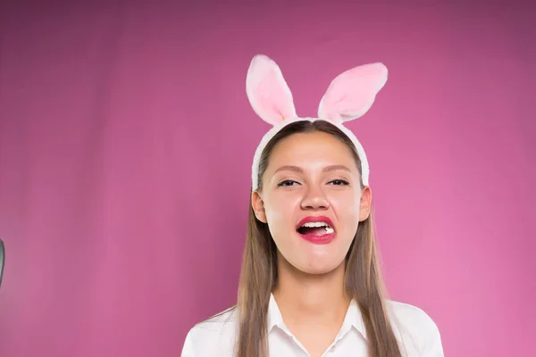 Una ragazza in rosa lepre orecchie masticare gomma da masticare — Foto Stock