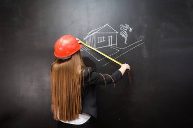 Kız inşaat kask içinde bir kara tahta üzerinde bir resmin, ölçer
