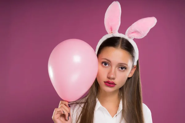 Una ragazza in orecchie di lepre rosa con un'espressione frustrata sul viso tiene un palloncino d'aria — Foto Stock