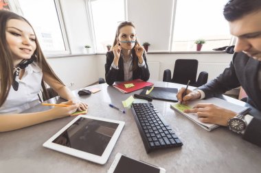 Üç genç insanlar ikindilerde bir şey tartışırken masada oturuyor