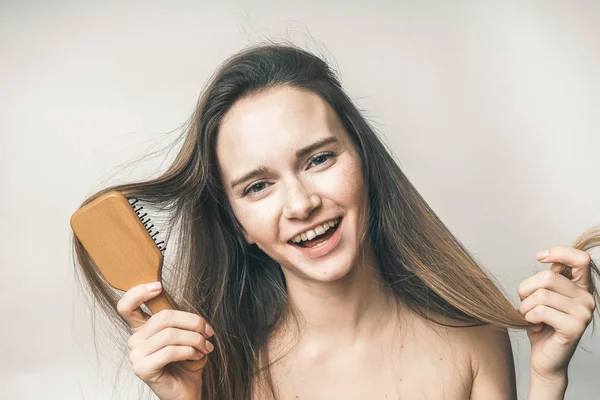 Mujer feliz sonríe con peine en la mano, belleza cuidado del cabello —  Fotos de Stock