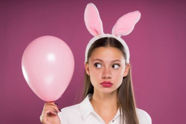 a girl with big eyes holds a pink ball and angrily looks away clipart