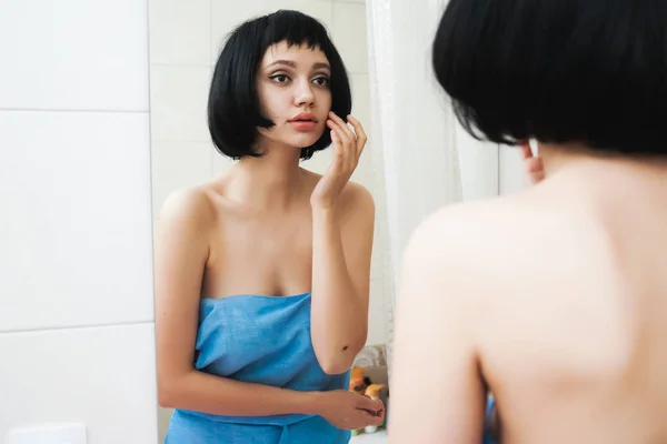 Дівчина з чорним волоссям оглядає себе у дзеркалі — стокове фото