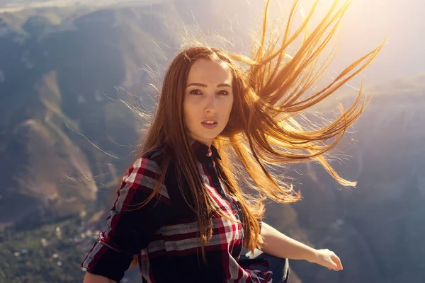 Lány úgy néz ki, a kamera, kockás ing, utat a hegyek, repülő haj, gyönyörű természet — Stock Fotó