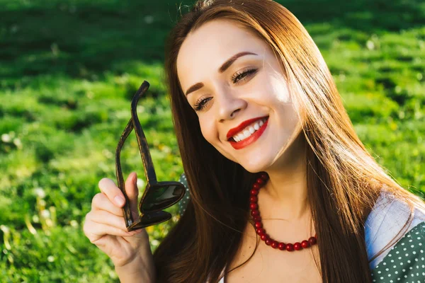 Gülümseyen kadın güneş gözlüğü, boşaltmak tutar. Gözlüklü, güneşli havalarda