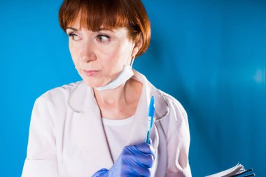 Korkmuş kadın hemşire beyaz paltolu kalem ve defter tutan