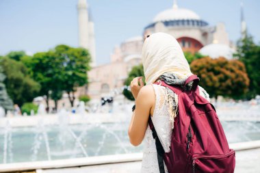 Bir eşarp ile cami ve Çeşme bir arka plan üzerine bir sırt çantası içinde tanınmayan bir kadın. Yaz tatili, gezgin