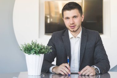 ofiste oturan ve kameraya bakarak elbiseli ciddi adam