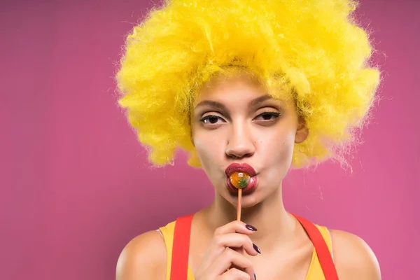 A glamorous girl eats chupachups, looks into the camera. Clown — Stock Photo, Image