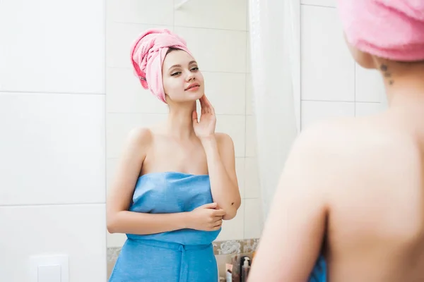 Дівчина захоплюється чистою шкірою, робить маску для волосся, дивиться на себе у дзеркало у ванній — стокове фото