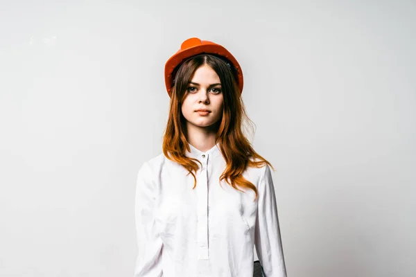 Menina bonita em um chapéu laranja e camisa branca olha para a câmera — Fotografia de Stock