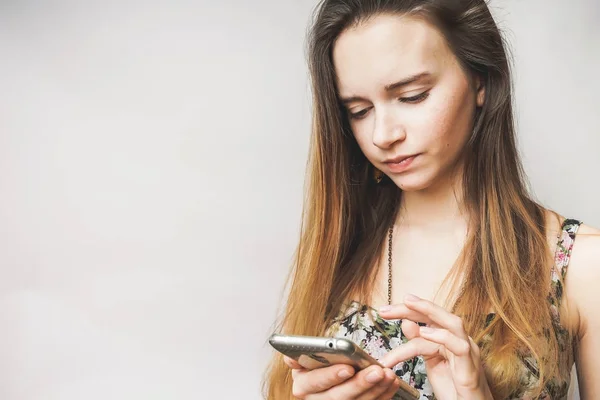 Mujer joven busca en smartphone, enviar mensajes de texto, cabello largo — Foto de Stock