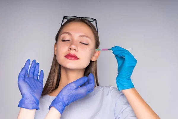 Linda menina com cabelos longos em um casaco branco vai fazer-se uma injeção — Fotografia de Stock