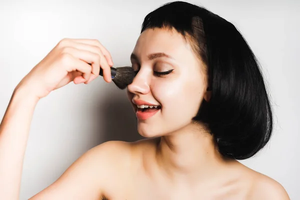 Ragazza con capelli neri corti dipinge il viso con una spazzola — Foto Stock