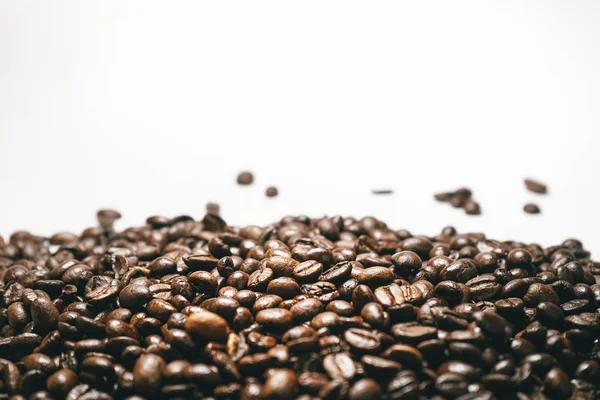 tahıl düşen beyaz bir arka plan üzerinde kahverengi kahve çekirdekleri yakın çekim