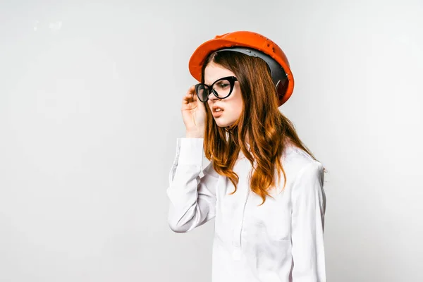 Hermosa chica en camisa blanca y sombrero naranja sostiene gafas — Foto de Stock