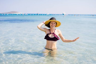 Bel-derin denizde duran şapkalı gülümseyen kız