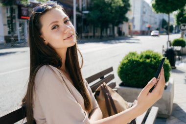 bir bankta oturan selfie yaparken güneş gözlüğü gülümseyen kız