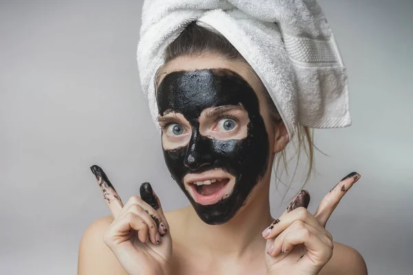 Mujer alegre sonriente obtiene máscara negra en la cara. Cuidado de la piel, poros limpios, exfoliación — Foto de Stock